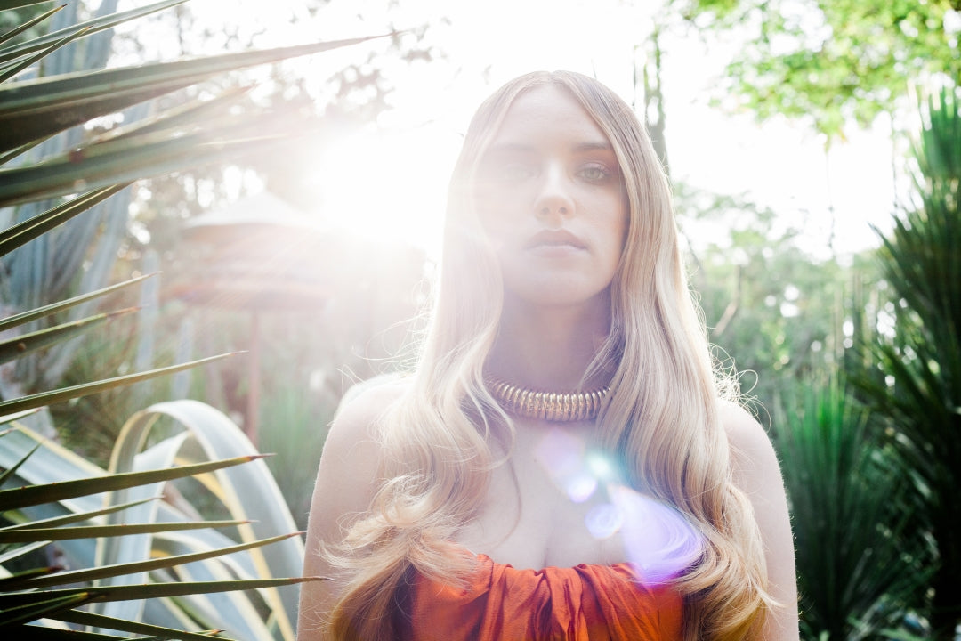Blonde hair in direct Mediterranean sun with tropical plants — why UV protection matters for hair in Cyprus